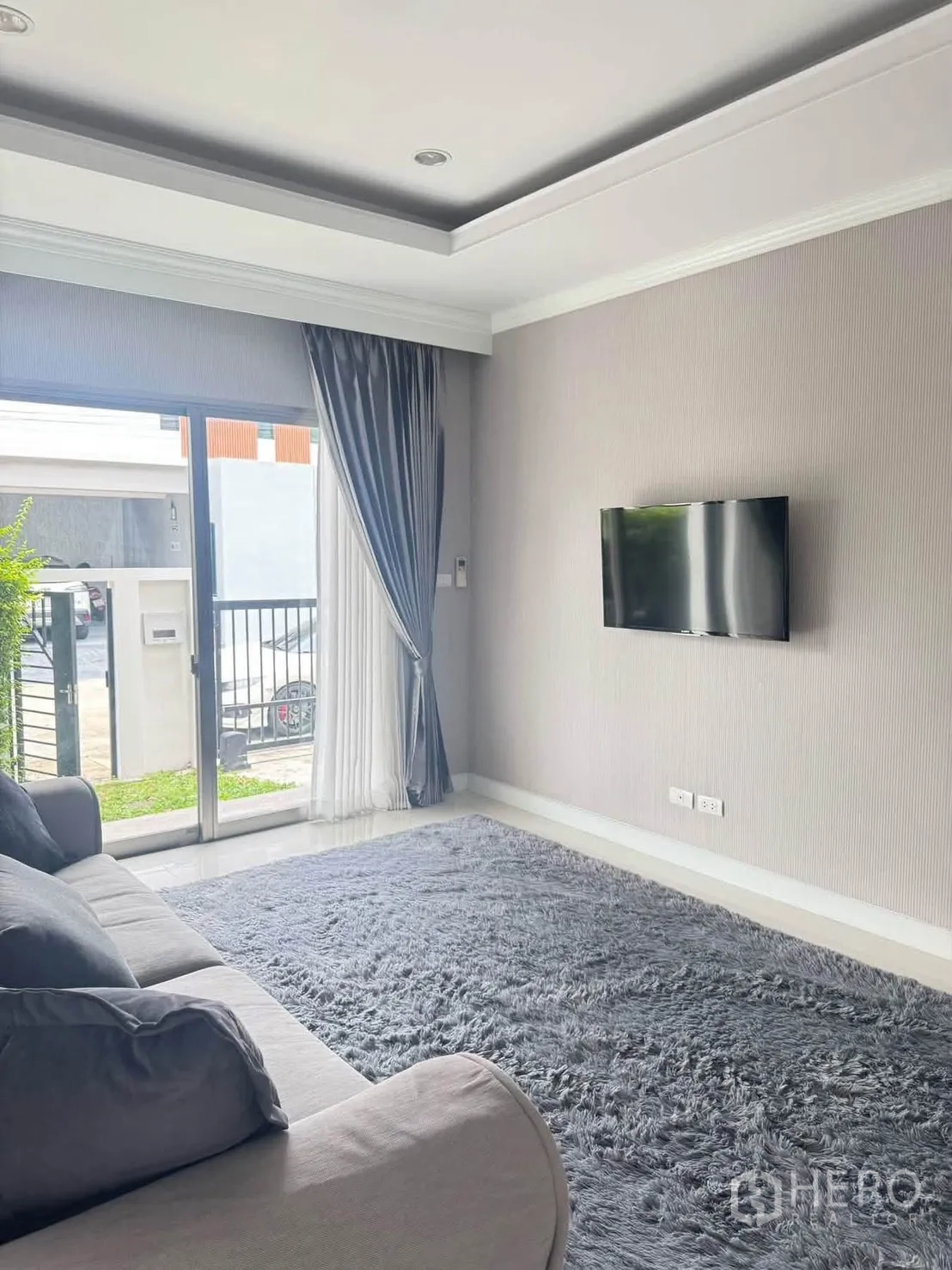 半独立式住宅 for rent or sale in Suan Luang, Bangkok - 次客厅设壁挂电视、沙发与长绒地毯，推拉门连通前院。