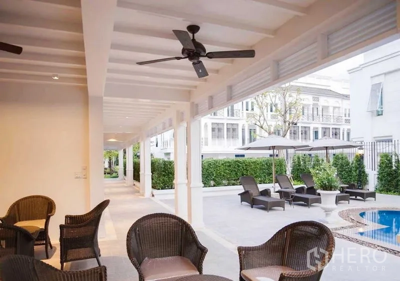Townhouse for rent in Phra Khanong, Bangkok - Covered terrace with rattan chairs overlooking the pool deck.