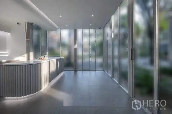 Retail Space for rent in Khlong Toei, Bangkok - Bright modern retail interior with a curved service counter, floor-to-ceiling glass walls and grey tile flooring.