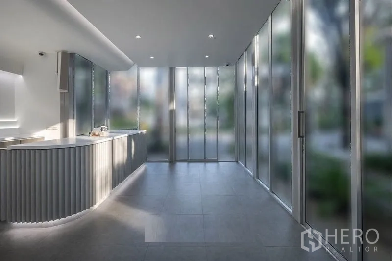 Retail Space for rent in Khlong Toei, Bangkok - Bright modern retail interior with a curved service counter, floor-to-ceiling glass walls and grey tile flooring.