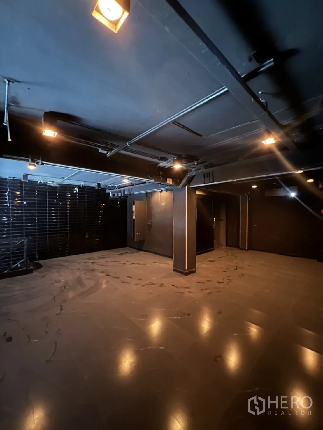 Home Office for rent or sale in Khlong Toei, Bangkok - Dark open-plan interior with tiled floors, structural columns and warm spotlights.