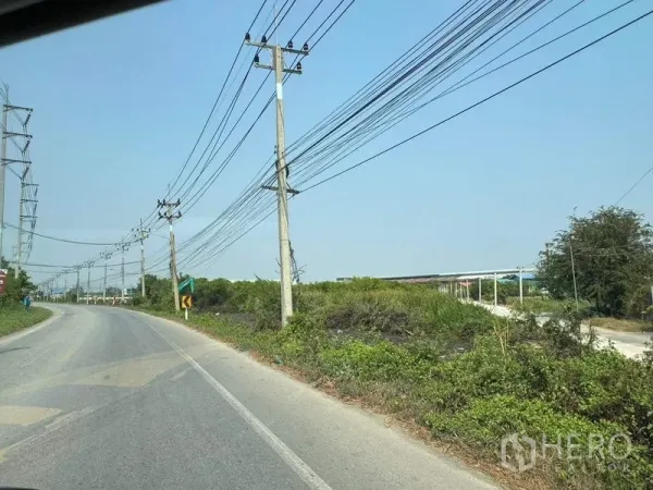 Land for sale in Mueang Samut Sakhon, Samut Sakhon - Two-lane road with power poles beside undeveloped roadside land.