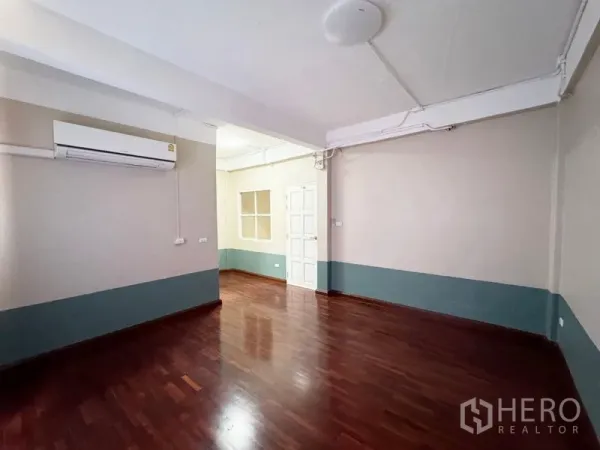 Townhouse for rent or sale in Suan Luang, Bangkok - Empty room with polished wooden floors, air conditioner and white door