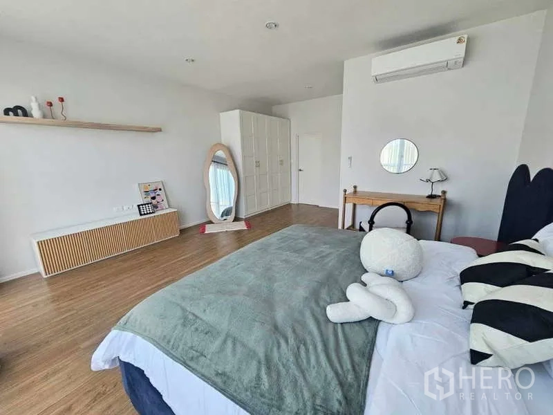 Townhouse for rent in Suan Luang, Bangkok - Spacious master bedroom with wood floors, large bed, wardrobe, air conditioner and full-height windows.