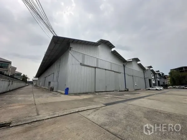 货栈 出租在Pak Kret, Nonthaburi - 大型金属板仓库外观，带宽阔车道与装卸场地。