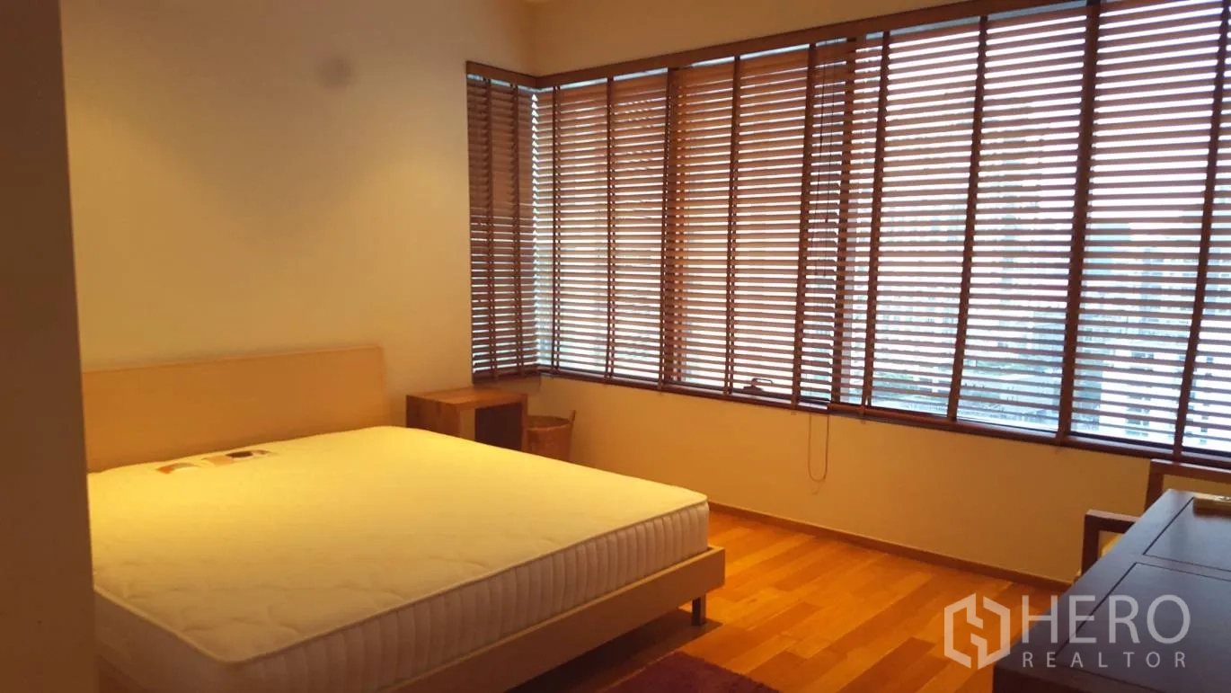 Condominium for rent or sale in Khlong Toei, Bangkok - Master bedroom with corner windows and wood blinds, king bed and nightstands.