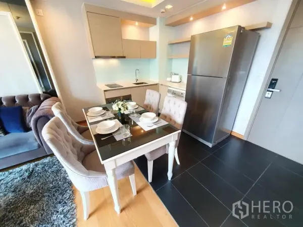 Condominium for rent in Watthana, Bangkok - Modern kitchenette with stainless fridge, washing machine and a four-seat dining table in a Watthana condo.