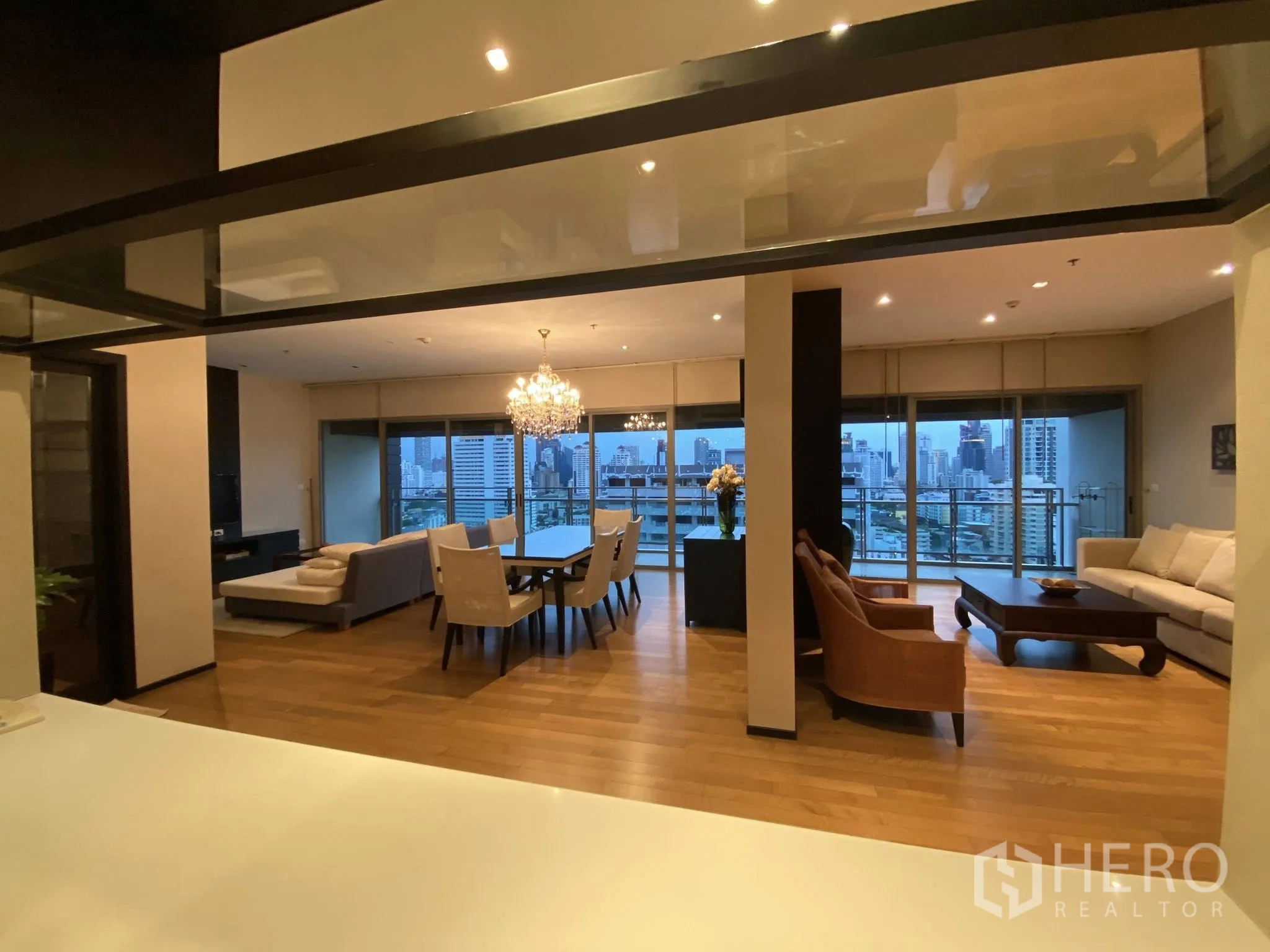 คอนโด for rent in Watthana, Bangkok - ห้องรับแขกกว้างพร้อมหน้าต่างเต็มบาน ระเบียง และวิวสกายไลน์ยามเย็น