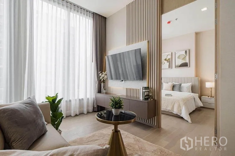 Condominium for rent in Watthana, Bangkok - Living room with mounted TV feature wall and sliding access to the bedroom.