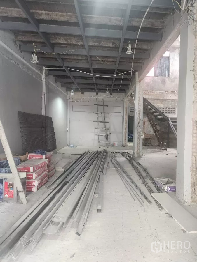 Shophouse for rent in Watthana, Bangkok - Ground floor space with exposed steel beams and neatly stacked building materials.