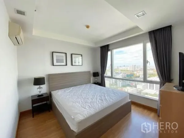 Condominium for rent in Huai Khwang, Bangkok - Master bedroom with large window, city skyline view and double bed.