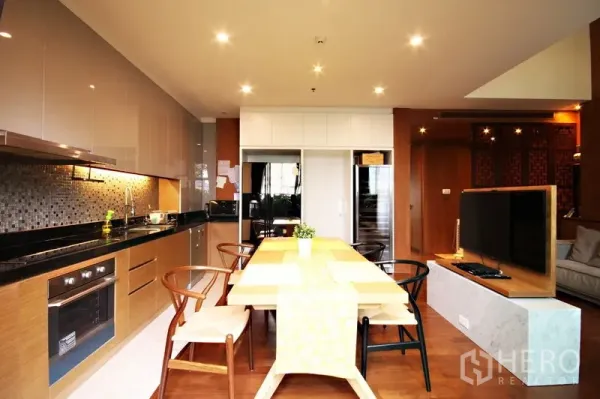 Condominium for rent or sale in Khlong Toei, Bangkok - Open-plan kitchen and dining with mosaic backsplash, wood cabinetry, and a TV partition.