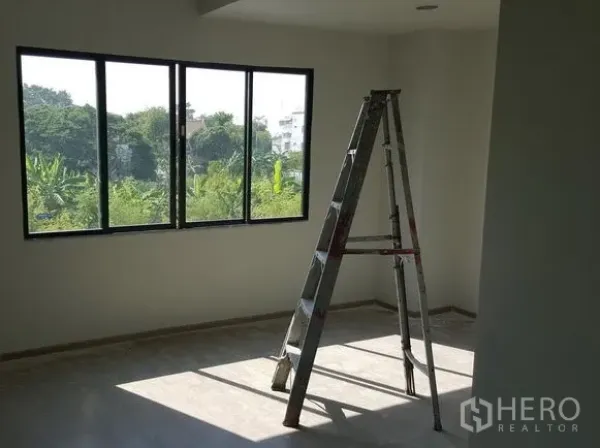 Townhouse for rent in Bueng Kum, Bangkok - Spacious bedroom with wide window and green neighborhood view, filled with natural light.