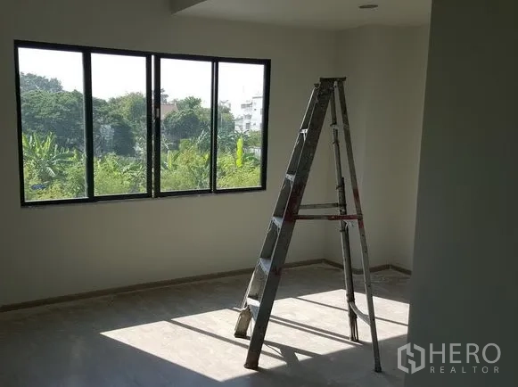 Townhouse for rent in Bueng Kum, Bangkok - Spacious bedroom with wide window and green neighborhood view, filled with natural light.