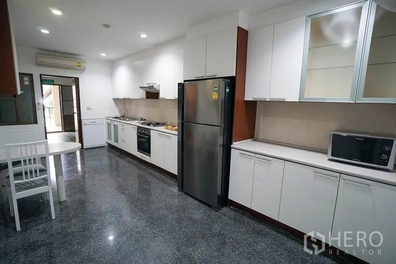房间 出租在Watthana, Bangkok - 明亮主厨房，白色橱柜、燃气灶、烤箱与不锈钢冰箱。