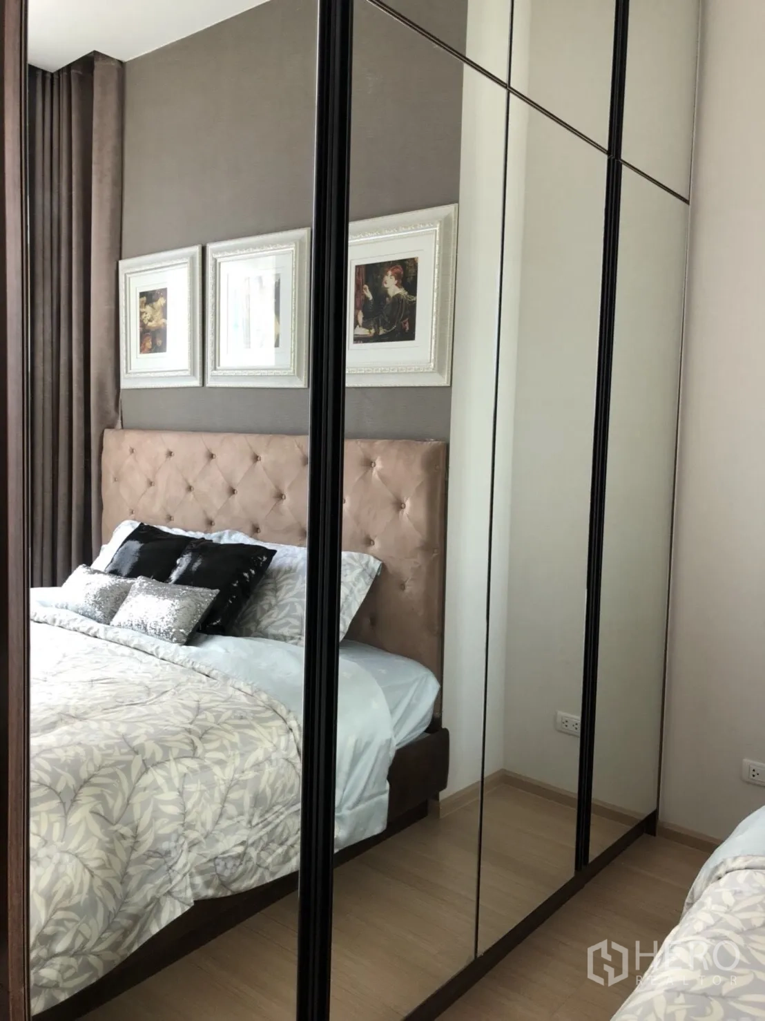 Condominium for rent or sale in Huai Khwang, Bangkok - Close-up of bedroom showing mirrored wardrobe doors reflecting the bed and artwork.