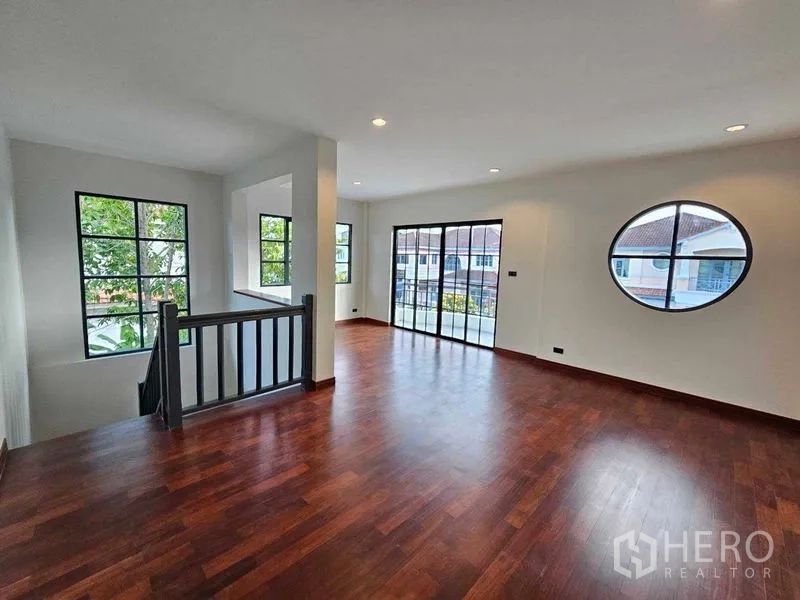 Detached House for sale in Thanyaburi, Pathum Thani - Upstairs family area with wooden floors, circular window, and balcony doors.