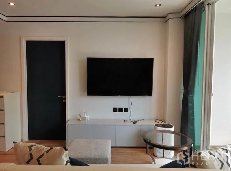 Condominium for rent in Sathon, Bangkok - TV wall with mounted flat screen and console beside large sliding balcony doors.