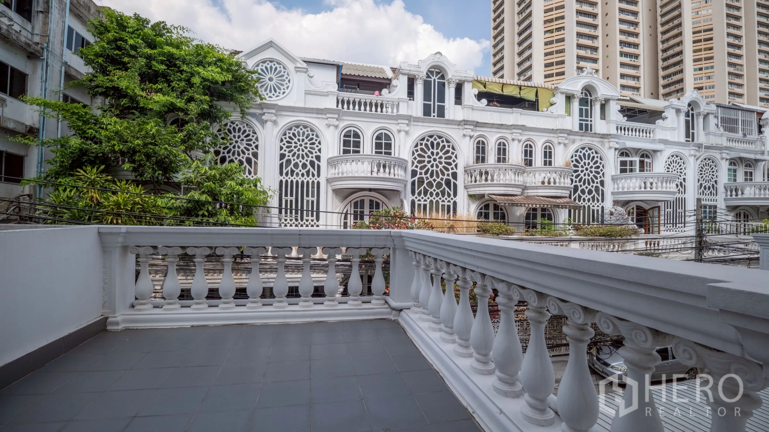 Townhouse for rent in Khlong Toei, Bangkok - Large terrace with balustrade facing ornate white townhouses and high-rises.