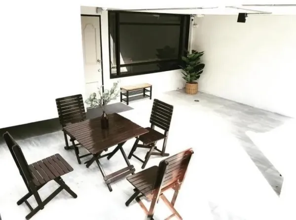 Townhouse for rent in Chatuchak, Bangkok - Covered terrace with folding wooden table and chairs beside a large window.