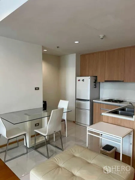 Condominium for rent in Ratchathewi, Bangkok - Open kitchenette with wood cabinets, refrigerator, and glass dining table.