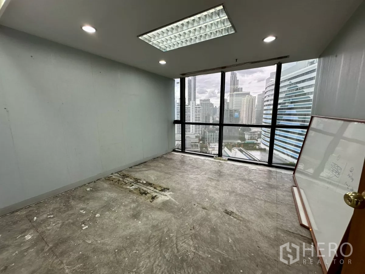 办公空间 出租在Khlong Toei, Bangkok - 带全高窗户的独立办公室，可观城市景观，墙边靠着白板。