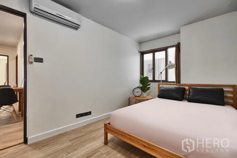 Condominium for rent in Watthana, Bangkok - Cozy bedroom with wooden bed frame, window, air conditioning and bedside table.