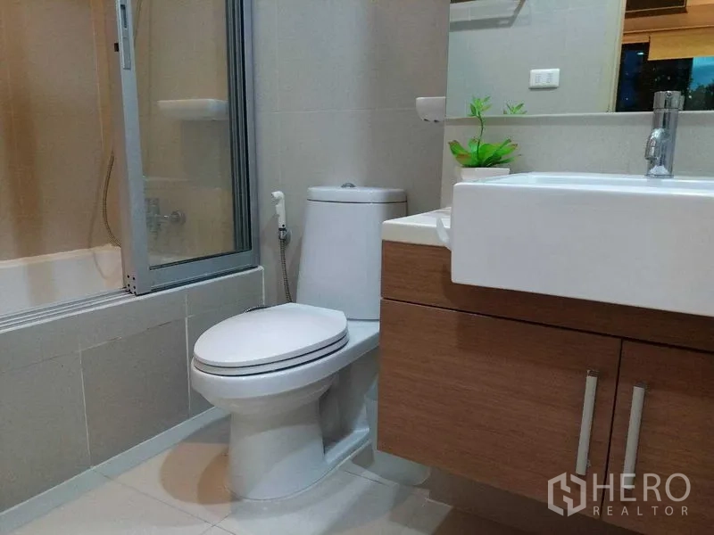 公寓 出售在Watthana, Bangkok - 现代卫浴，浴缸带玻璃隔断，台盆柜与坐便器。