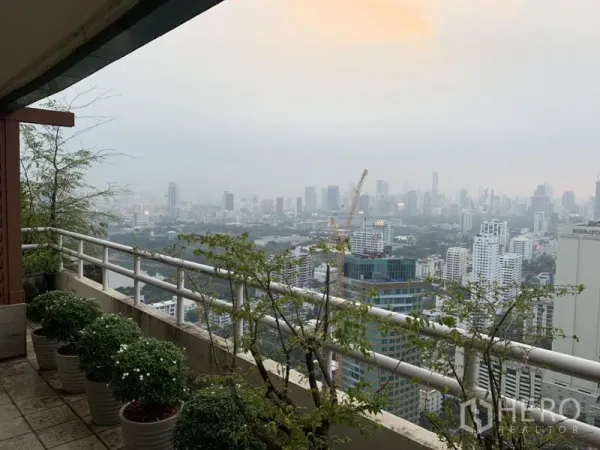 公寓 出租或出售在Watthana, Bangkok - 高层阳台种有盆栽，可俯瞰曼谷城市天际线全景。