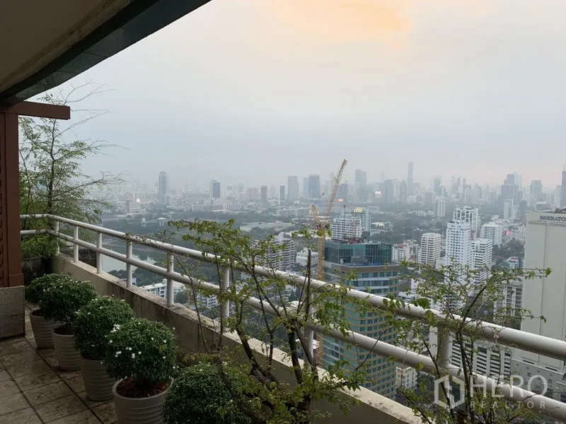 公寓 出租或出售在Watthana, Bangkok - 高层阳台种有盆栽，可俯瞰曼谷城市天际线全景。