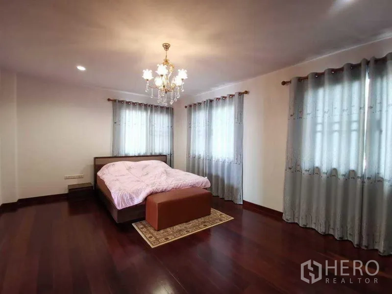 บ้าน ให้เช่าในPrawet, Bangkok - ห้องนอนโปร่งสว่าง โคมไฟระย้า หน้าต่างมุมห้อง ผ้าม่านสีเทา และพื้นไม้