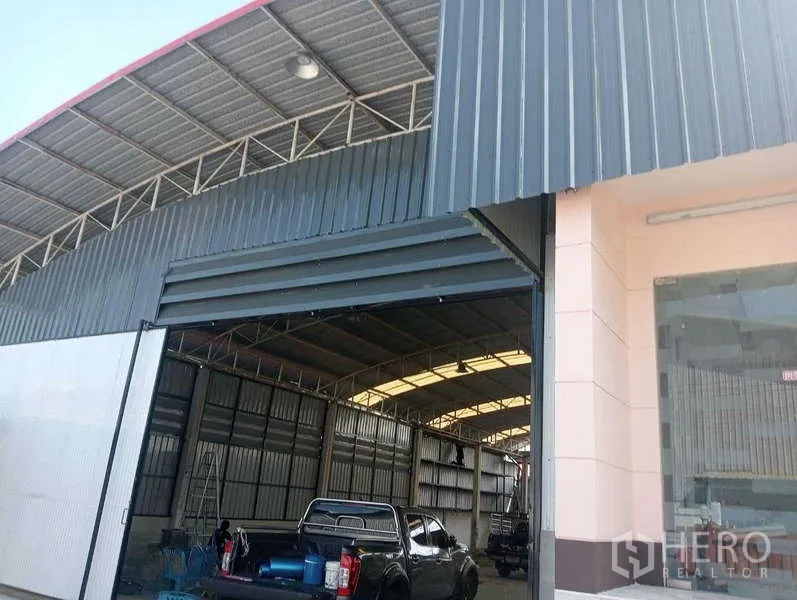Warehouse for rent in Lam Luk Ka, Pathum Thani - Close-up of warehouse entrance featuring steel roller door and glass-front office section.