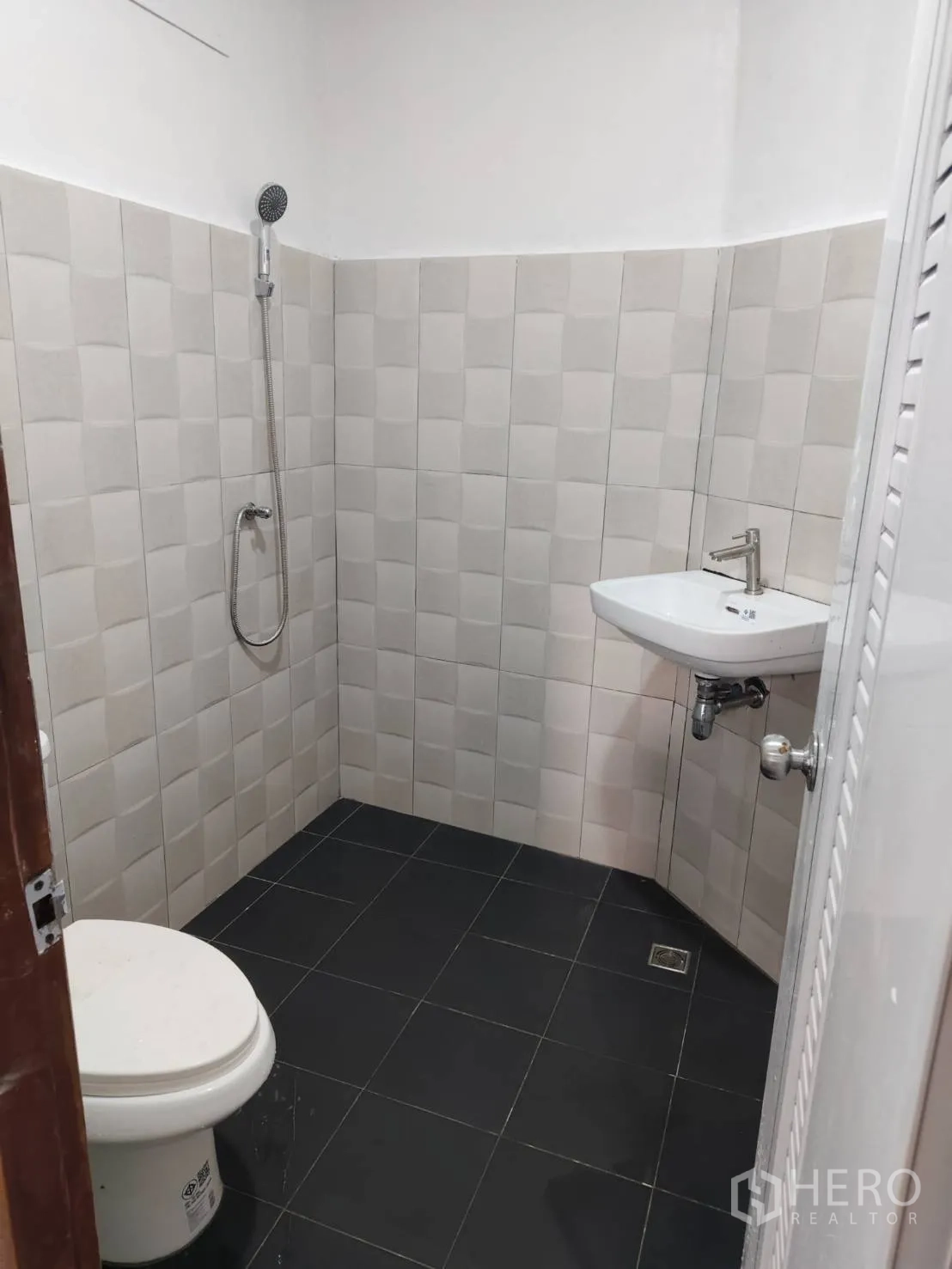 Townhouse for sale in Phra Khanong, Bangkok - Renovated bathroom with handheld shower, toilet and wall-mounted sink.
