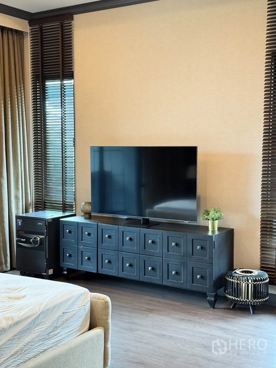 Detached House for rent in Bang Kapi, Bangkok - Master bedroom TV console with large screen, dark cabinet, and window blinds.