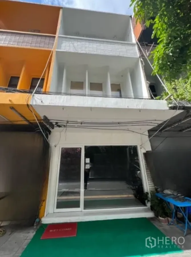 Shophouse for rent or sale in Khlong Toei, Bangkok - Three-storey shophouse facade with glass storefront and balcony near Ekkamai BTS.