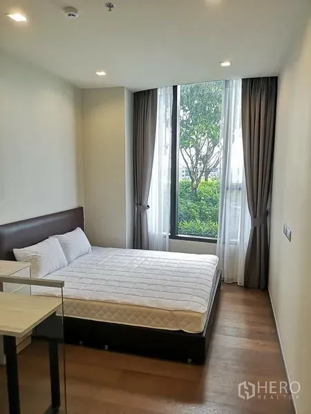 公寓 出租在Ratchathewi, Bangkok - 明亮卧室，双人床与落地窗，可见绿景，Ideo Q Victory。