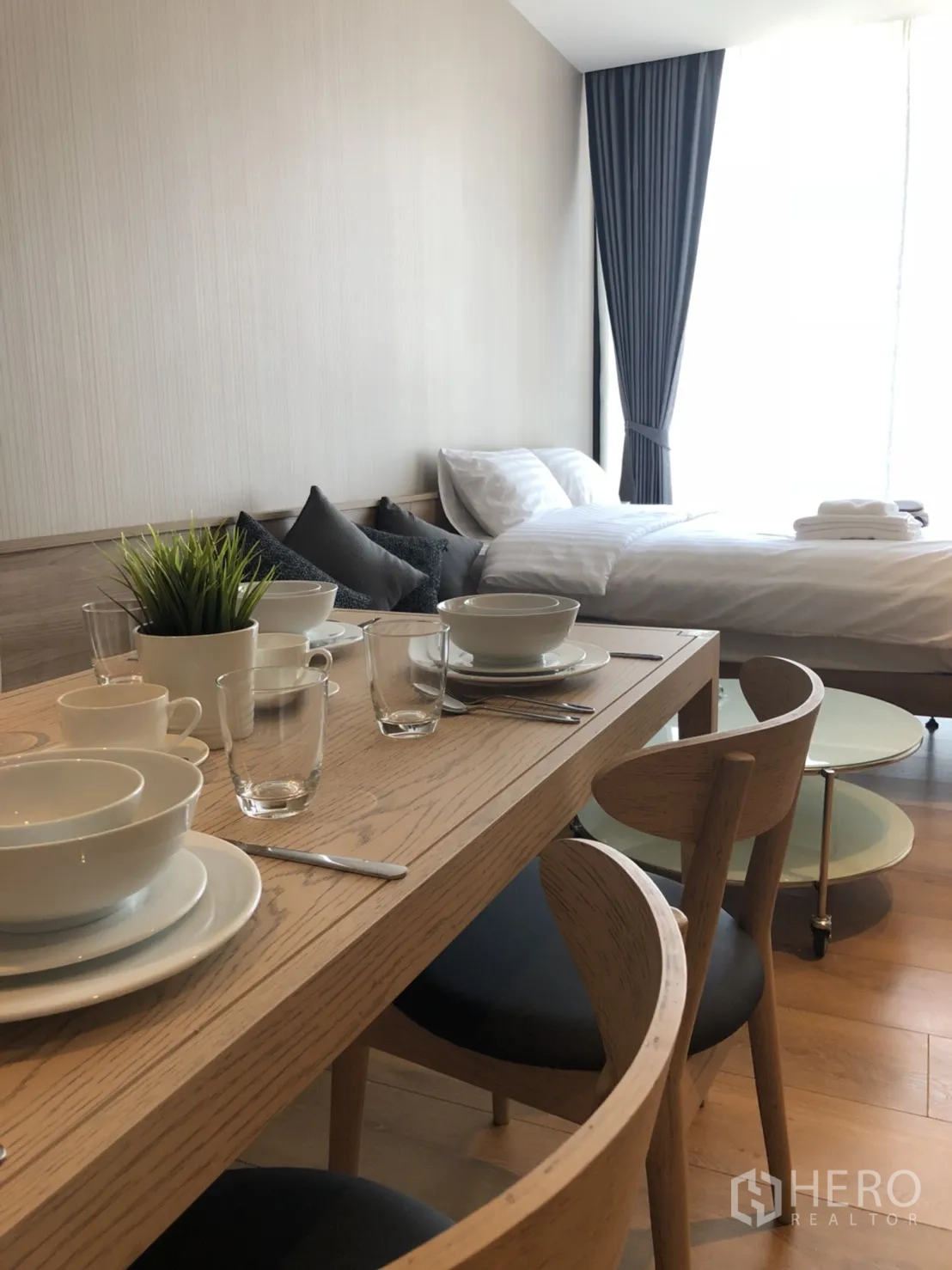 公寓 出租在Khlong Toei, Bangkok - 现代公寓内，卧区靠近大窗，配有双人餐桌。