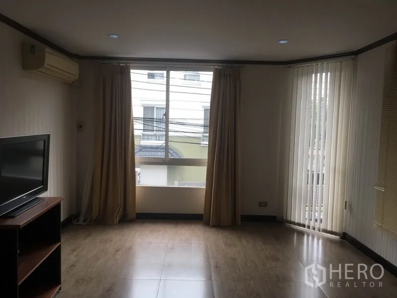 Townhouse for rent in Din Daeng, Bangkok - Upper-level family room with TV stand, wide windows and curtains.