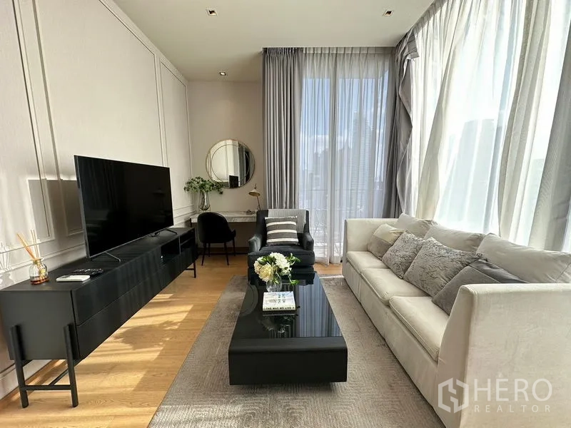 公寓 出租在Pathum Wan, Bangkok - 起居区配长款电视柜、茶几、沙发和窗边工作台。