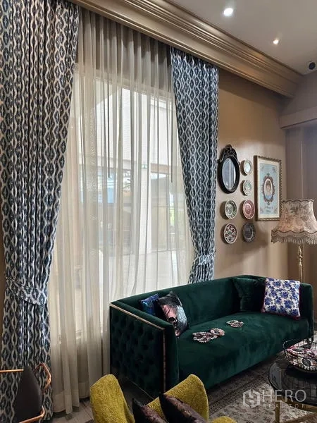 Retail Space for rent in Khlong Toei, Bangkok - Cozy lounge area with tall patterned curtains, a green velvet sofa, and decorative wall plates beside a large window.