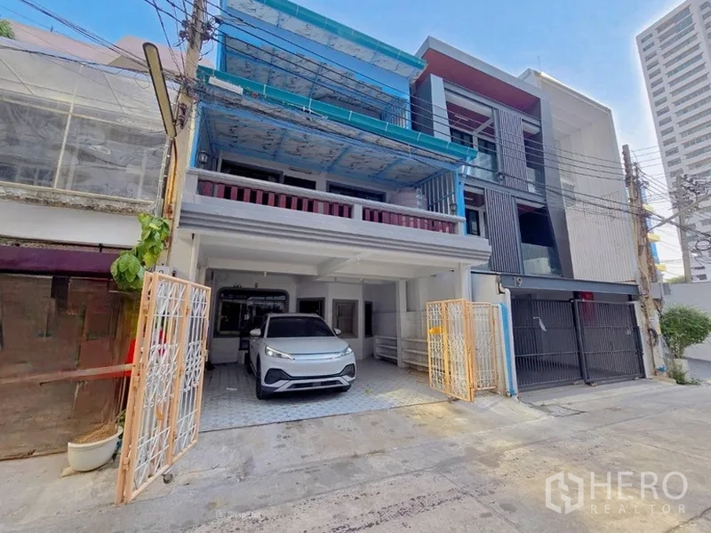 Home Office for rent in Sathon, Bangkok - Open sliding gate revealing covered carport parking beside modern neighboring townhomes.