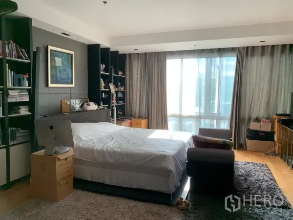 Condominium for sale in Khlong Toei, Bangkok - Spacious bedroom with large windows, built-in shelves and a plush rug.