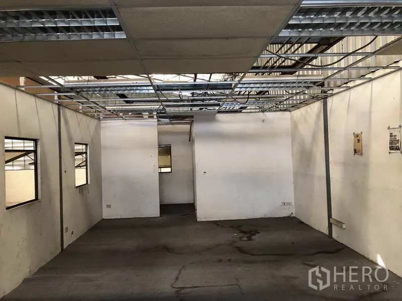 Warehouse for rent in Suan Luang, Bangkok - Partitioned office area under renovation with exposed ceiling grid and windows.