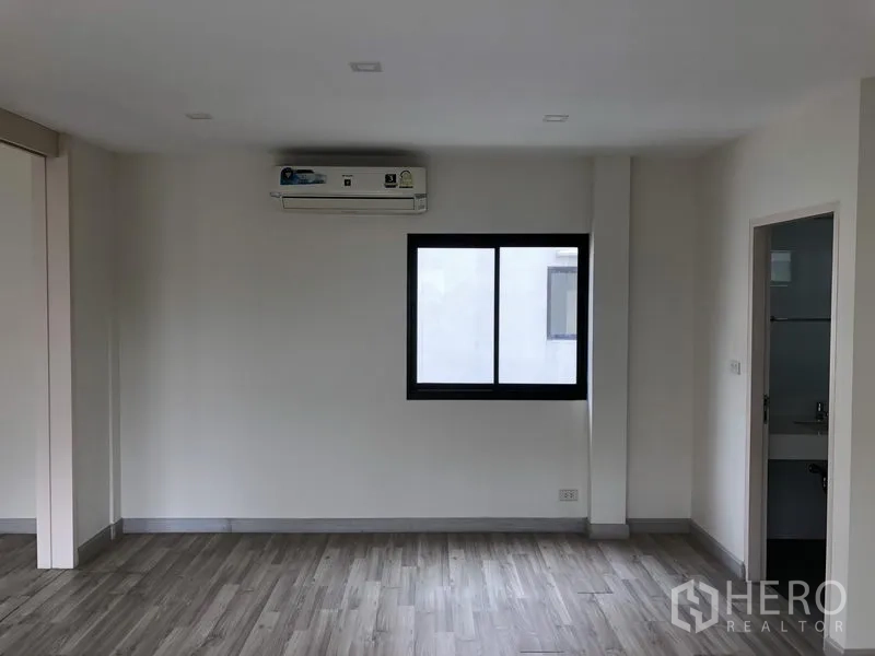 Townhouse for rent or sale in Saphan Sung, Bangkok - Bedroom with window, air conditioner and door to a bathroom.