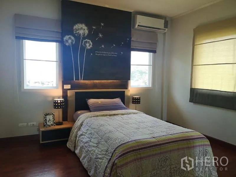 独立式住宅 出租 - 转角卧室，花卉装饰墙，床头灯、空调与双窗。