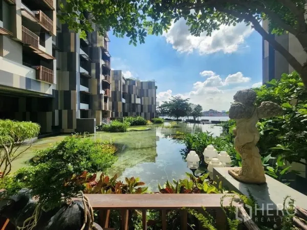 公寓 出售在Yan Nawa, Bangkok - 临河公寓庭院，镜面水景与茂密绿化，现代立面映衬蓝天。