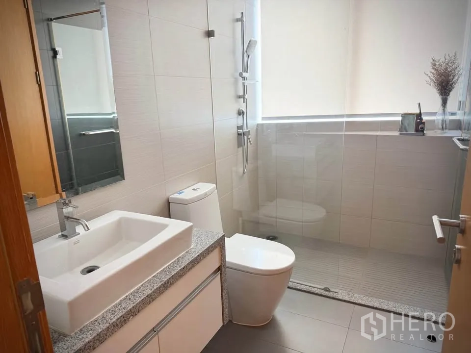 Condominium for rent or sale in Khlong Toei, Bangkok - Modern bathroom with square vanity, toilet, and a glass-enclosed shower area.