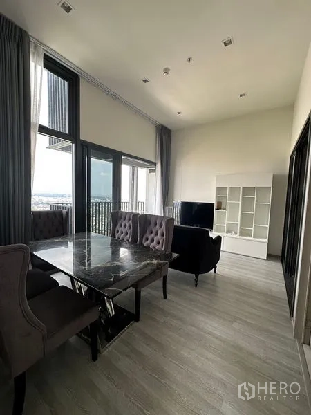 Condominium for rent in Phra Khanong, Bangkok - Open-plan dining and lounge with a marble dining table and large sliding doors to the balcony.