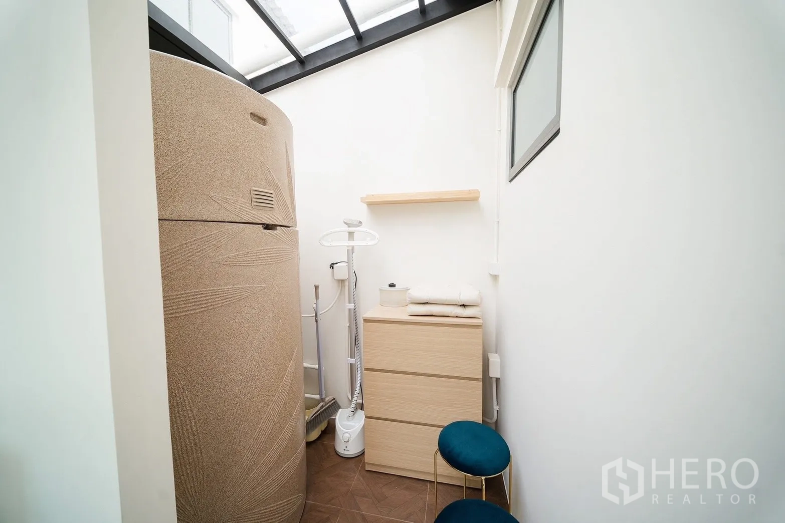 Townhouse for rent in Bang Phli, Samut Prakan - Skylit utility corner with a large water tank, storage cabinet, clothes steamer and stools.