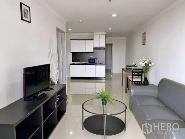 公寓 出租在Khlong Toei, Bangkok - 开放式起居区面向白色橱柜的紧凑厨房与电视柜。
